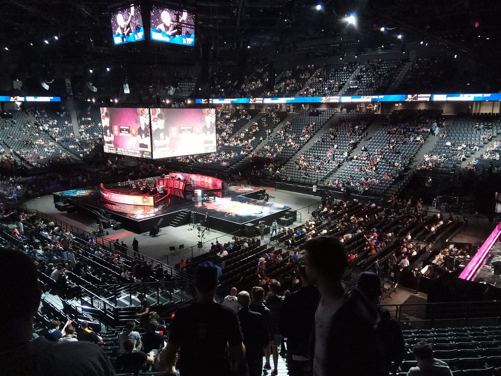 Arena lotada em torno de um palco iluminado durante uma final de campeonato de jogos eletrônicos