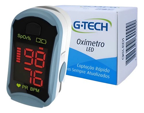 Oxímetro de dedo com visor de LED vermelho ao lado da caixa azul e branca