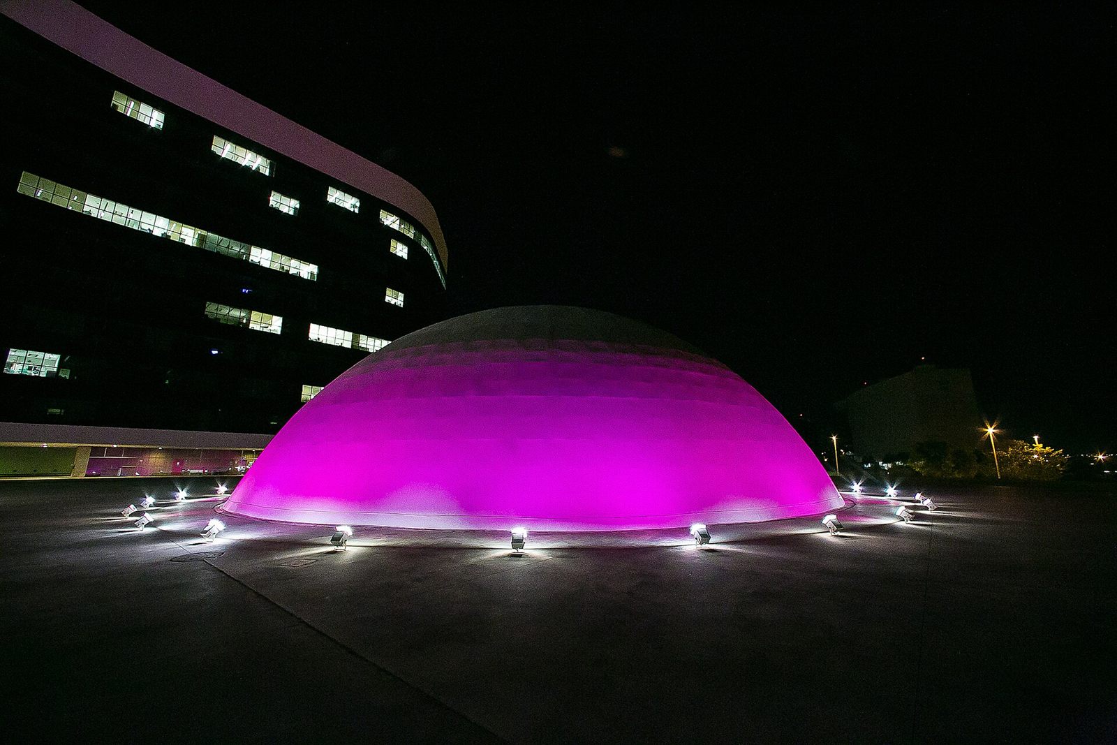 Cúpula de um edifício público em Brasília iluminada de rosa à noite, durante a campanha Outubro Rosa