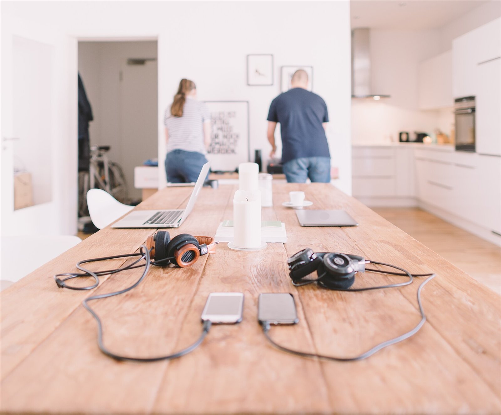 Mesa de madeira em uma casa, com notebooks, fones de ouvido e celulares